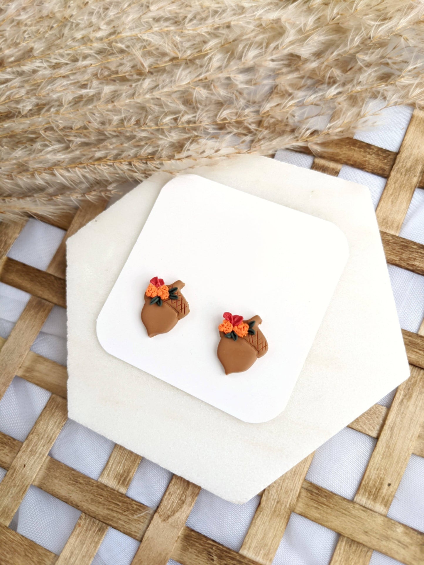 Pair of Floral Acorn Stud Earrings by, featuring handmade polymer clay acorn shapes adorned with orange and red flowers and green leaves