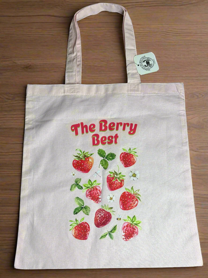 Light pink tote bag with red strawberries and “The Berry Best” text printed on the front