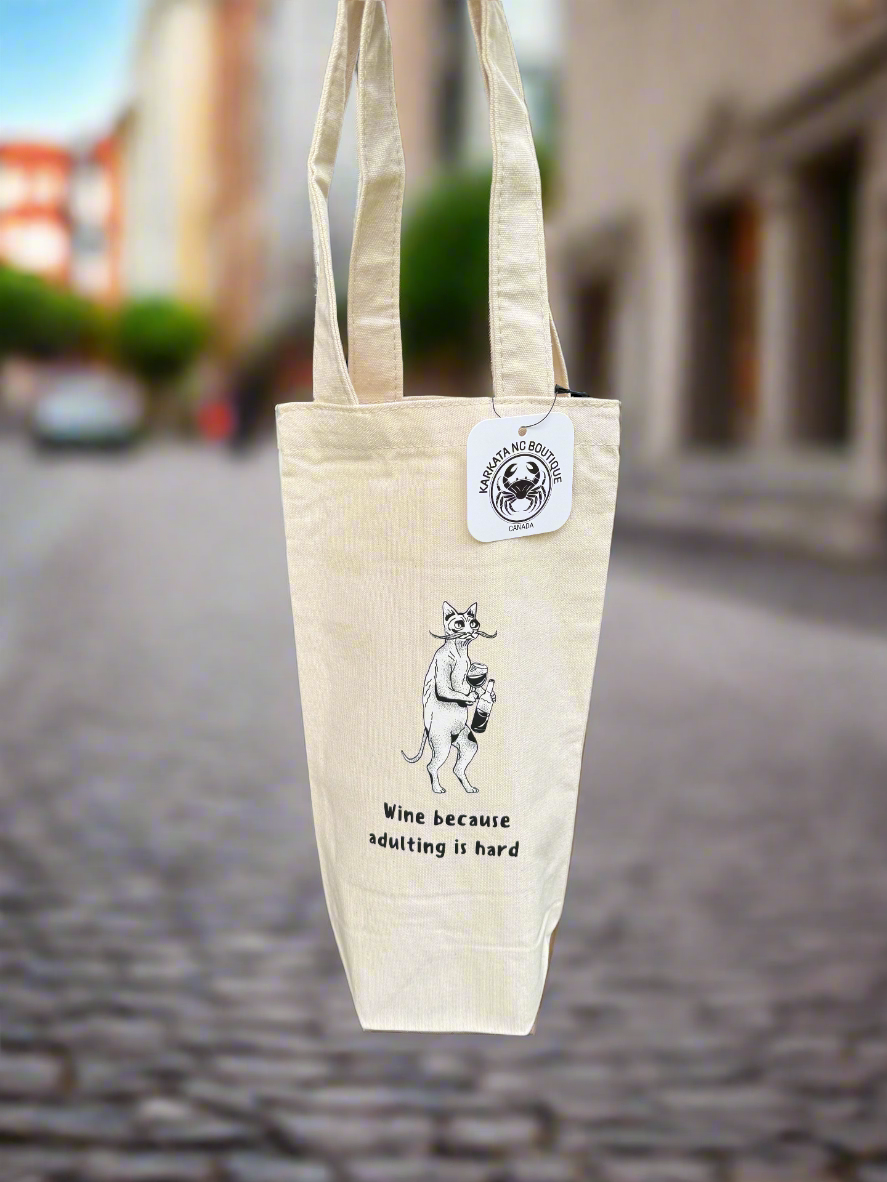 Canvas wine bag featuring the phrase "Wine because adulting is hard" with a humorous illustration of a quirky cat, designed by Karkata NC Boutique.