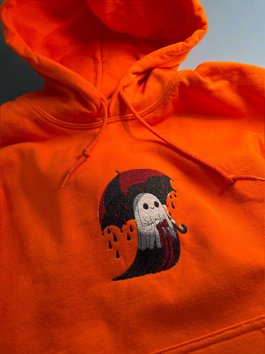 Front view of bright orange unisex fleece hoodie with embroidered ghost under umbrella design, perfect for Halloween