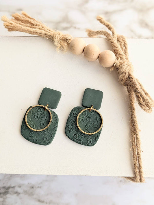 Pair of Christina Clay Dangle Earrings, featuring handmade green polymer clay charms embossed with floral patterns and adorned with textured gold hoops