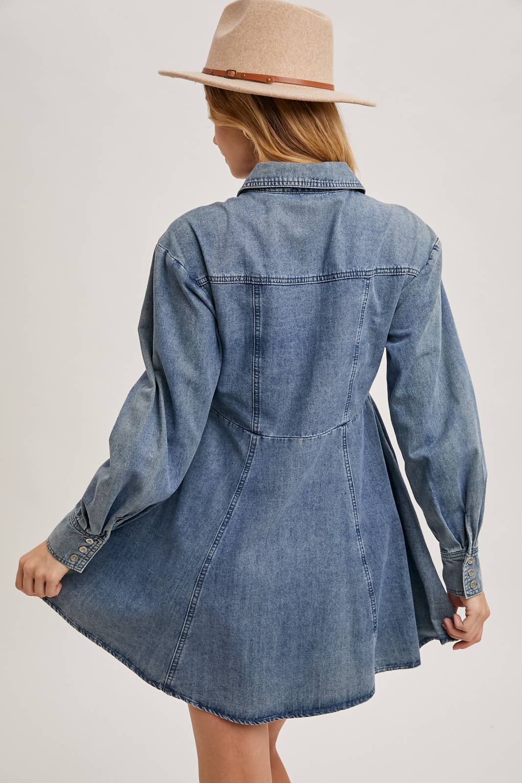 Back view of denim shirt dress, showing back yoke seam and slight flare, long sleeves