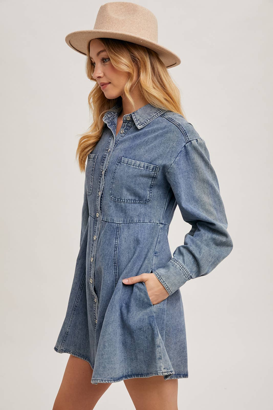 Side view of denim shirt dress with model wearing hat, displaying relaxed fit and long sleeve