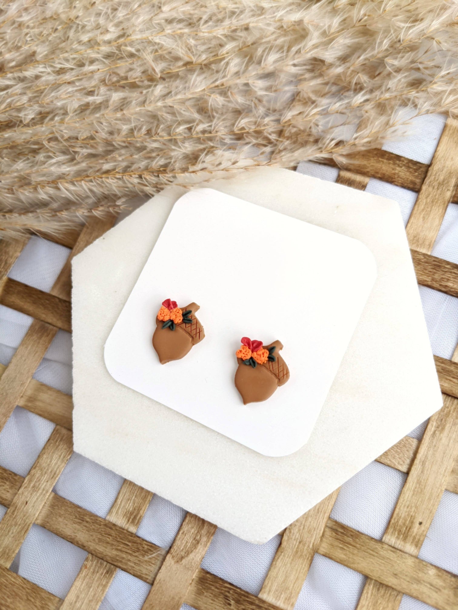 Pair of Floral Acorn Stud Earrings by, featuring handmade polymer clay acorn shapes adorned with orange and red flowers and green leaves