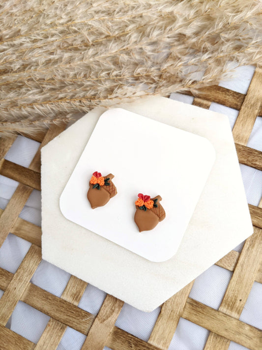 Pair of Floral Acorn Stud Earrings by, featuring handmade polymer clay acorn shapes adorned with orange and red flowers and green leaves