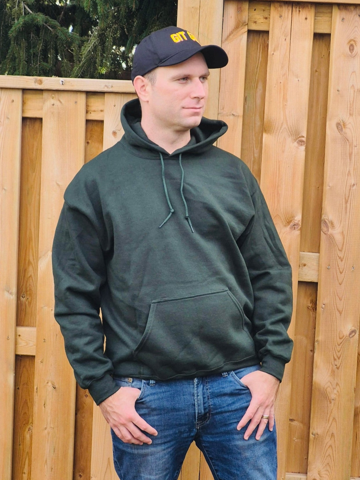 front view of male model wearing unisex forest green hoodie with drawstring hood and pocket
