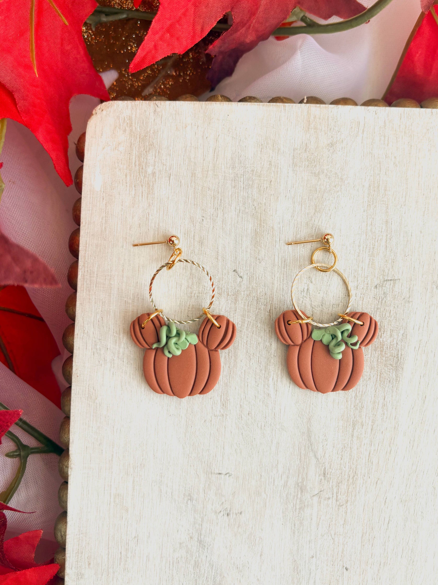 Pair of Halloween Dangle Earrings, featuring handmade pumpkin charms shaped like a mouse with green vine details and gold color twisted hoops, perfect for fall