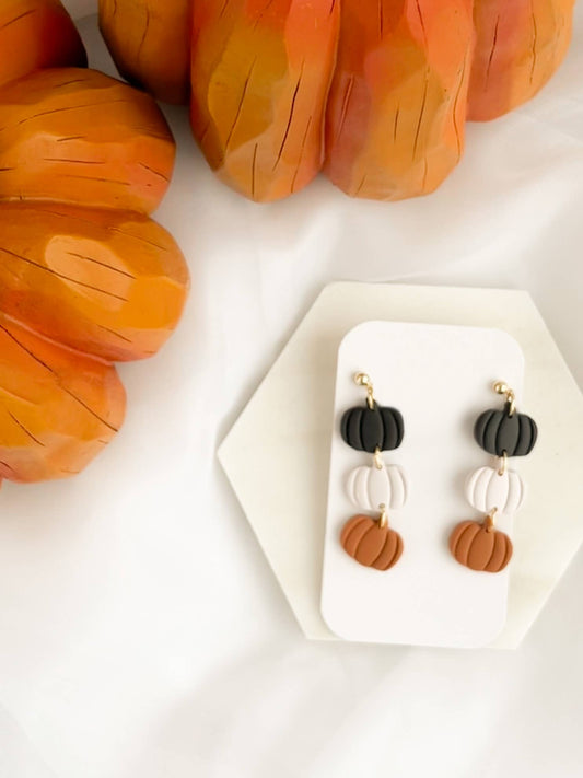 Pair of Halloween Dangle Earrings, featuring handmade clay pumpkins stacked in black, white, and orange colors on gold color hooks