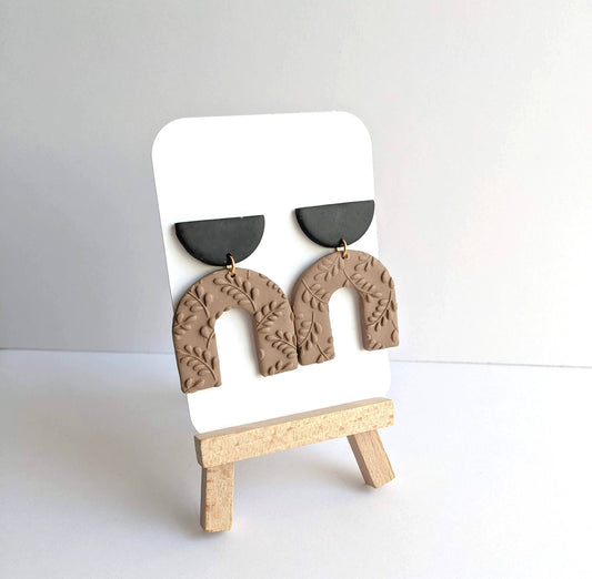 Pair of Harper Dangle Earrings, featuring handmade polymer clay arches with botanical impressions and matte black semicircle tops