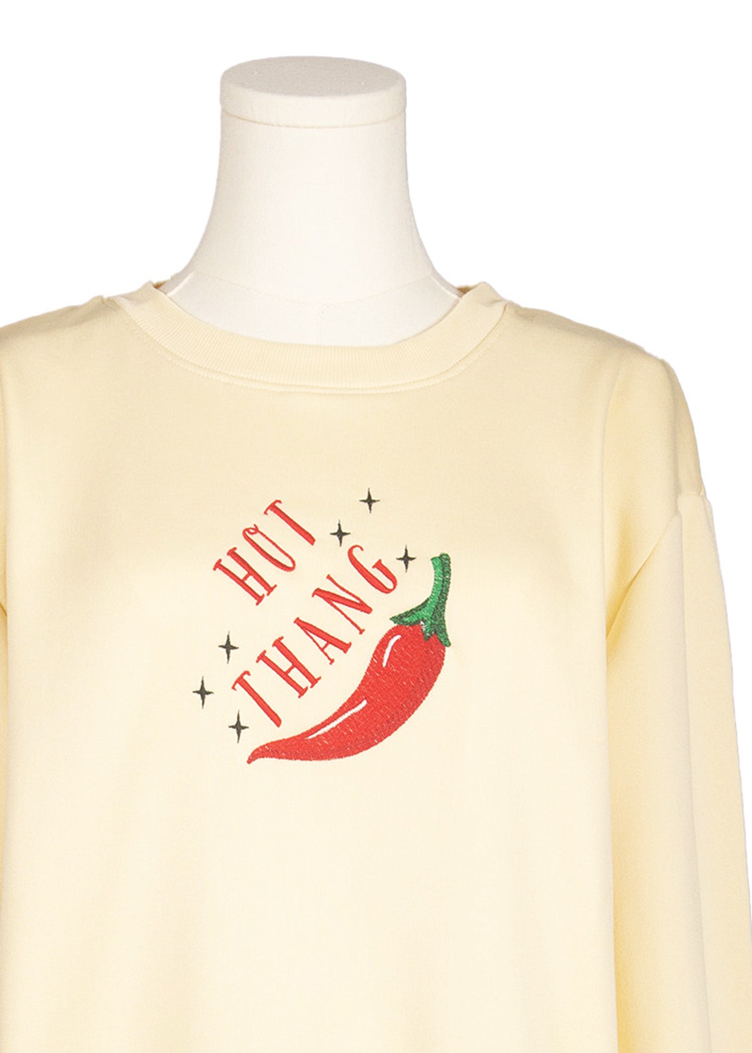 Close-up of beige sweatshirt with red chili and “Hot Thang” embroidered design, Canadian apparel