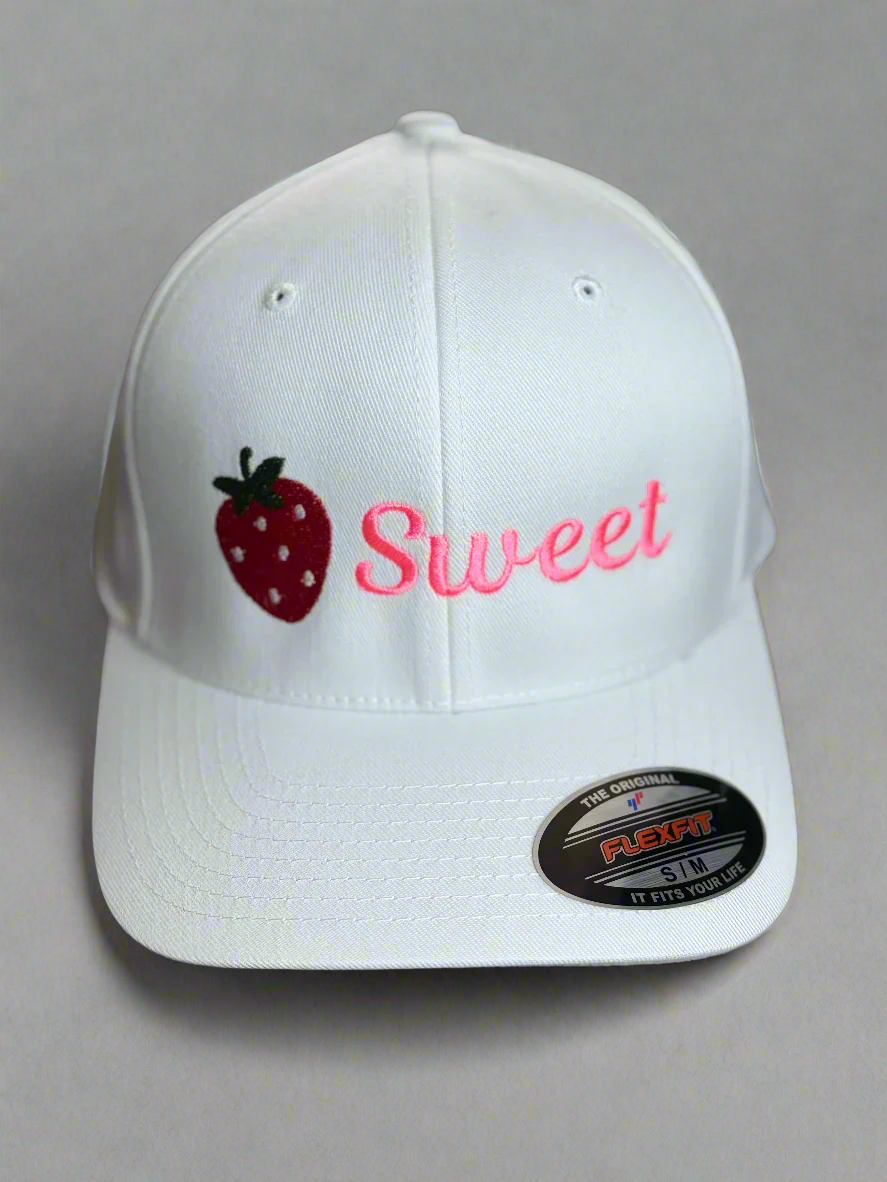 White hat with embroidered strawberry and the word “Sweet” in pink thread on the front
