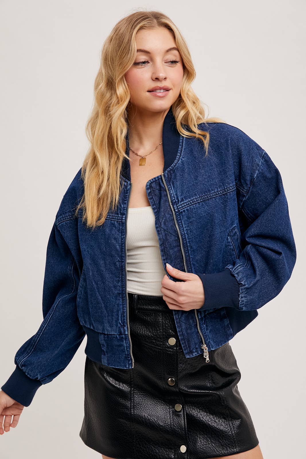 Close-up of zipped denim blue bomber jacket from Karkata NC Boutique showing ribbed cuff detail
