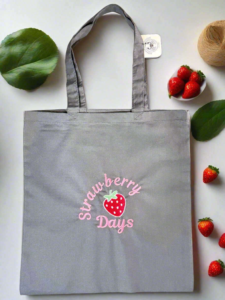 Charcoal grey cotton tote bag with pink 'Strawberry Days' embroidery and a red strawberry illustration