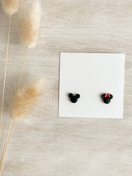 Pair of Magic Ears Micro Stud Earrings, featuring handmade polymer clay studs in black mouse head shapes, one adorned with a red polka dot bow