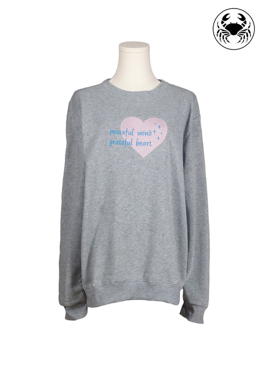 Front view of light grey sweatshirt with “peaceful mind, grateful heart” embroidered text, Canadian apparel
