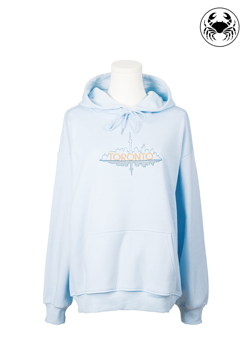 Front view of sky blue hoodie with embroidered outline of Toronto skyline, Canadian apparel