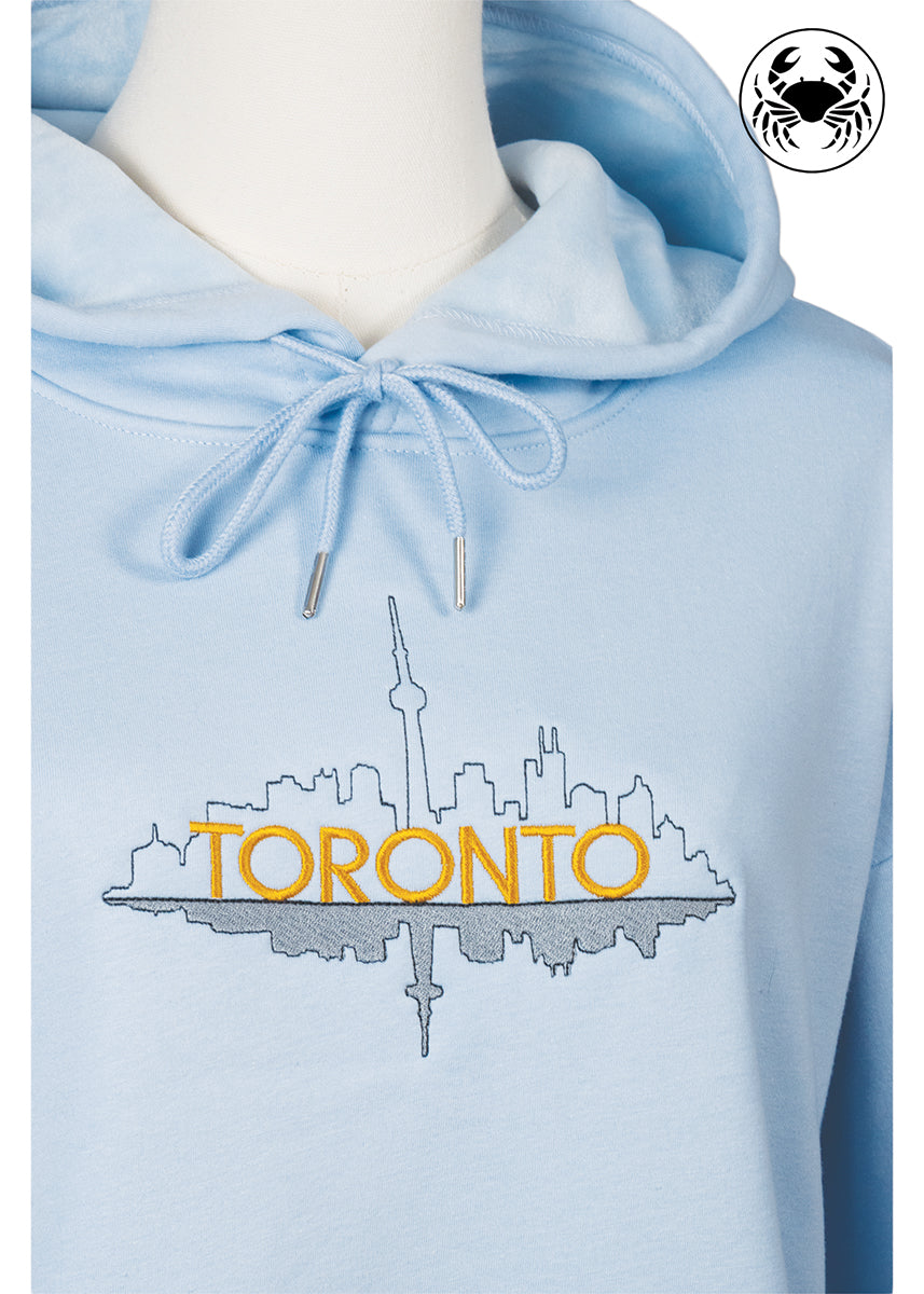 Close-up of embroidered Toronto skyline outline on sky blue hoodie, Canadian apparel